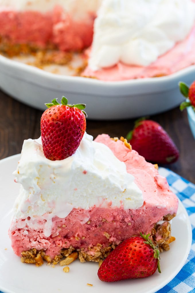 Slice of pie on a plate with rest of pie in background.