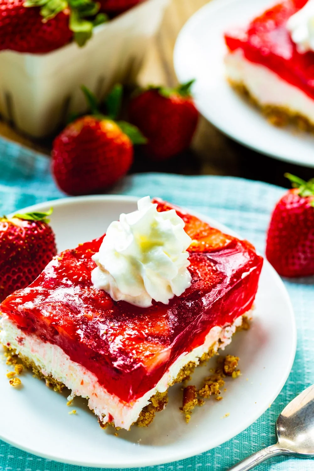 Slice of Strawberry Pretzel Salad with fresh strawberries around it.