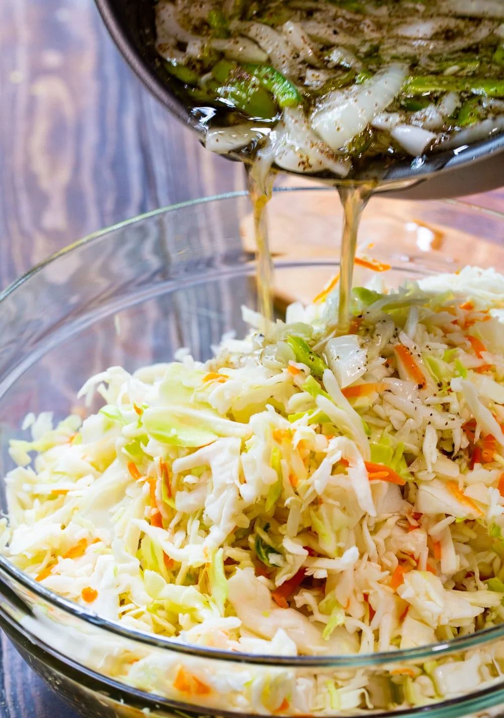 Vinegar mixture getting poured into bowl with cabbage.