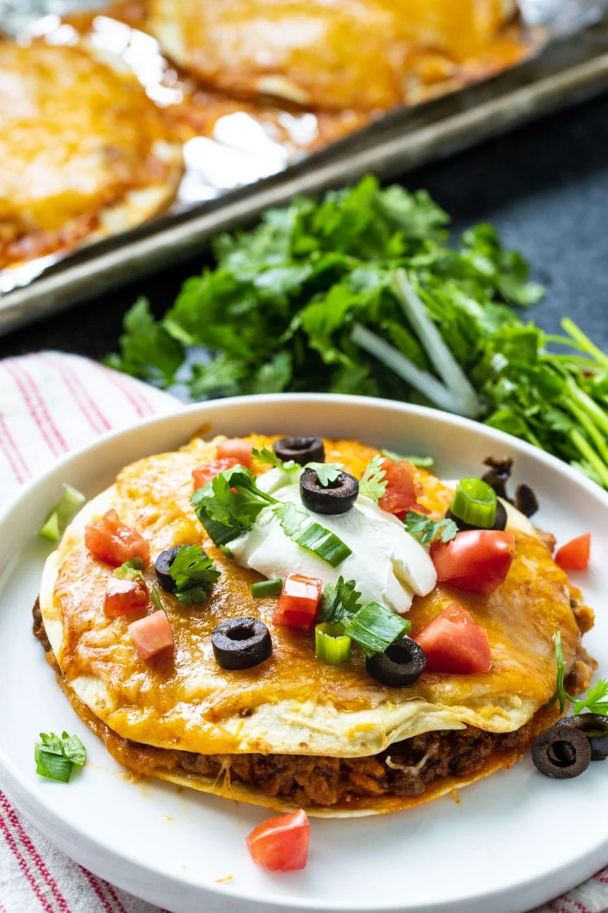 Mexican Pizza on a plate with cilantro in background.