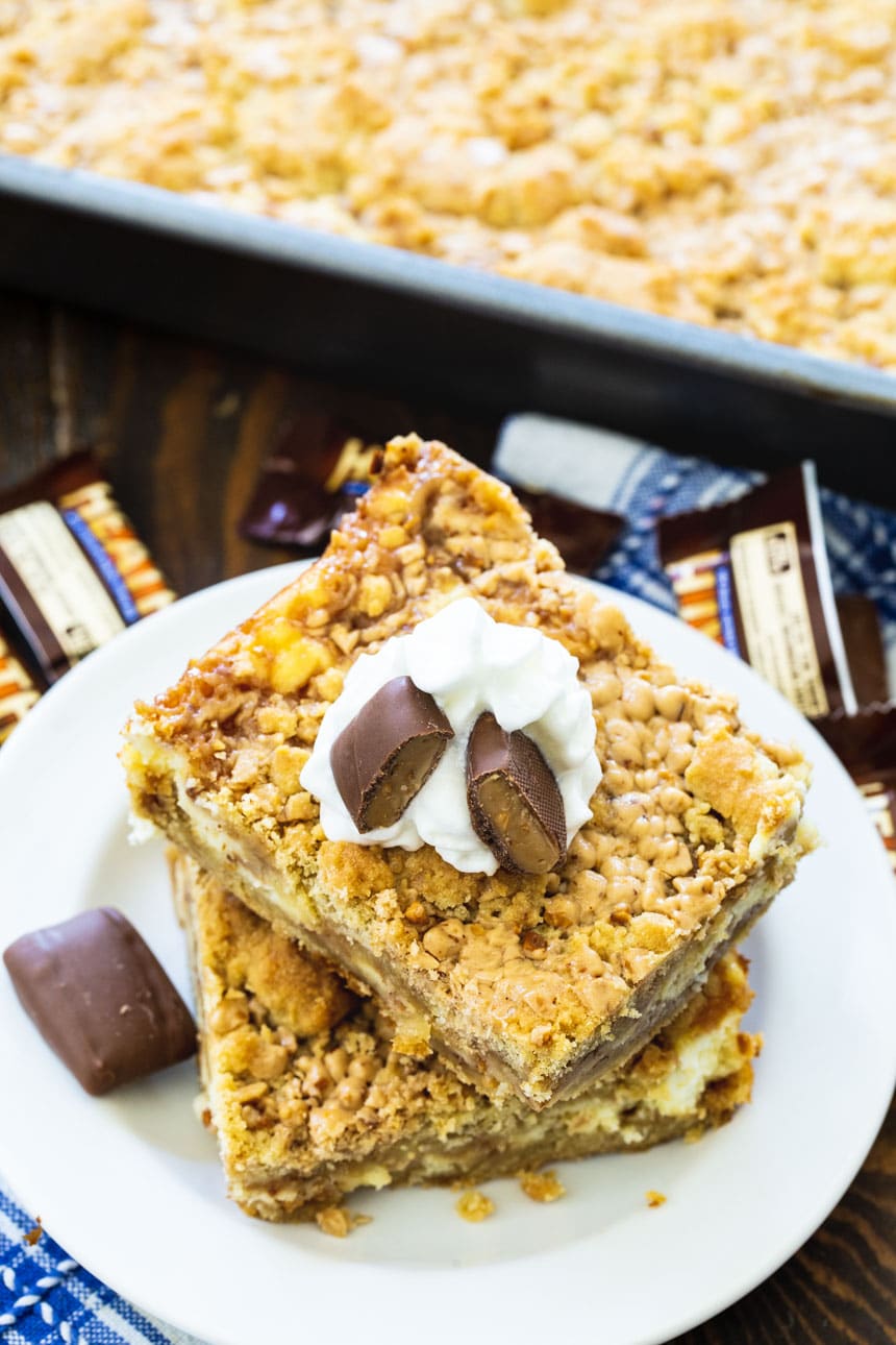 Toffee Cheesecake Bars on a plate with pan full of bars next to them.