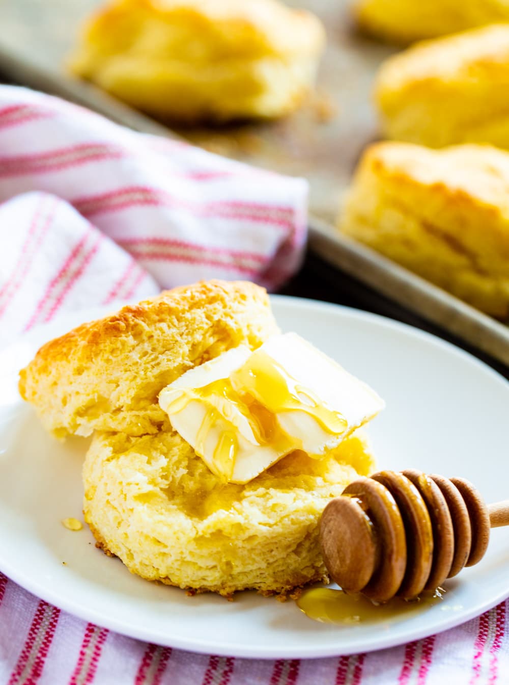 Biscuit split open and covered with butter and honey.