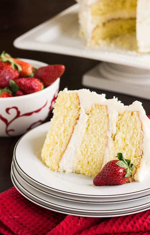 Almond Cake with Amaretto Filling on a white plate with bowl of strawberries in background.