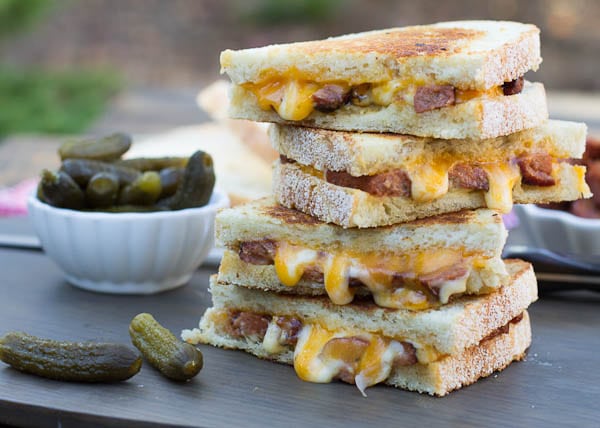 Grilled Cheese halves stacked on top of each other with bowl of pickles.