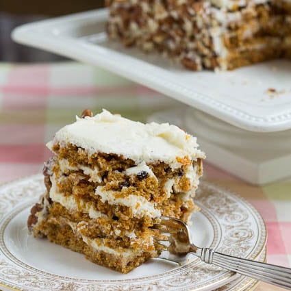 A slice of Carrot Cake on a Plate with a fork stuck in it.
