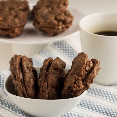 Three cookies arranged in a bowl with cup of coffee.