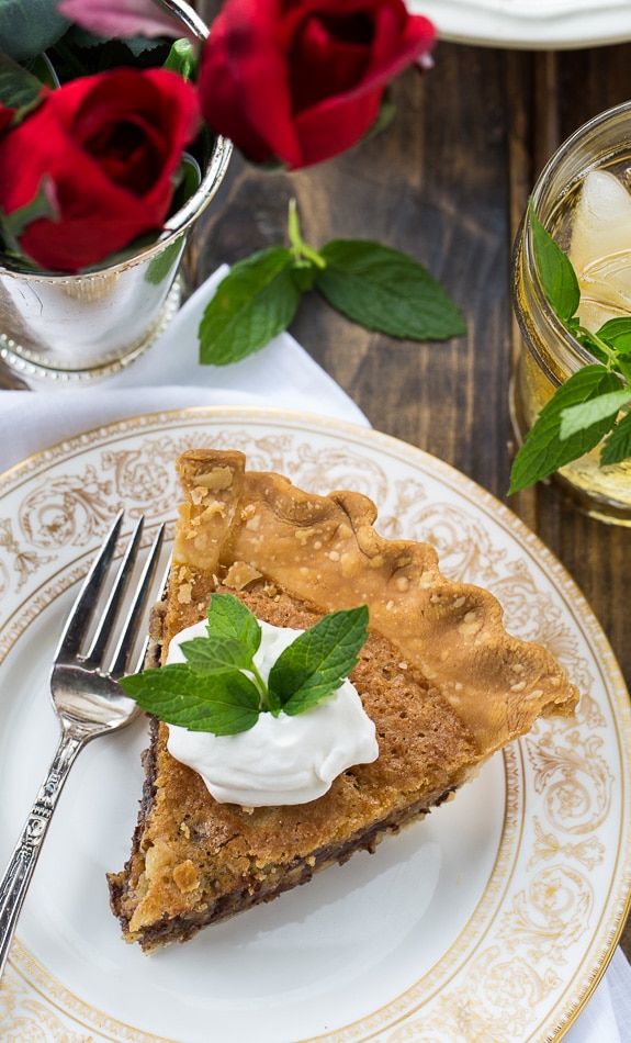 Kentucky Derby Pie has a gooey chocolate and walnut filling with a splash of bourbon. Top with bourbon whipped cream for a delicious southern dessert.