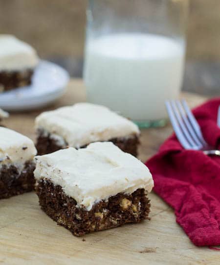Brownies arranged on wood board with milk in background.