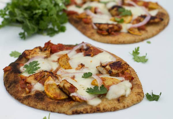 Chicken Tikka Pizza on naan bread surrounded by fresh cilantro.