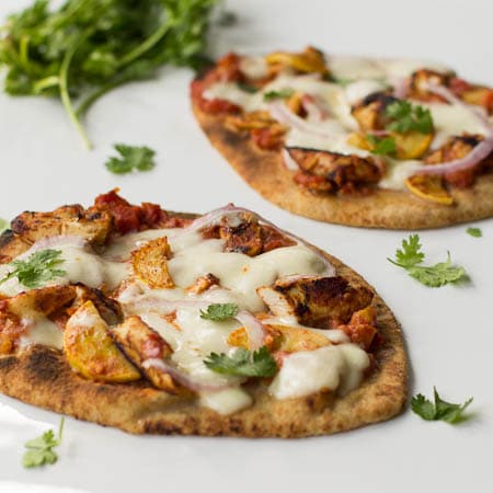 Two Chicken Tikka Pizzas on naan bread with fresh cilantro.