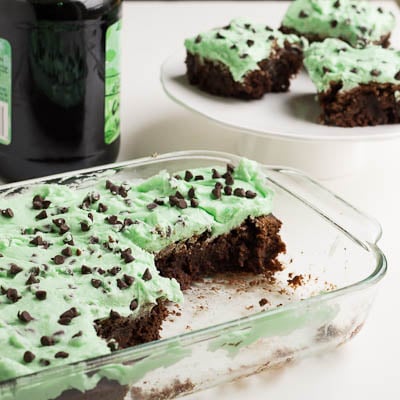 Baking dish with brownies and a bottle of creme de menthe in the background.