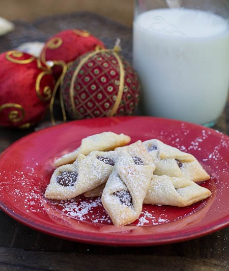 Bowtie Cookies on red plate with ornaments in background.