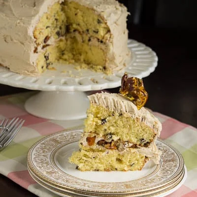 Slice of cake on a plate with the rest of the cake in the background.