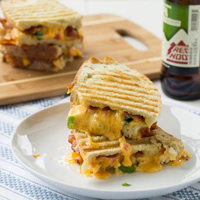 Pimiento Cheese Panini sandwich on a white plate with a beer.