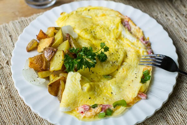 Pimiento Cheese Omelet with home fries on a plate with fork.