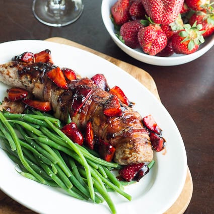 Pork Tenderloin with Balsamic Strawberries on a platter and a bowl of strawberries.