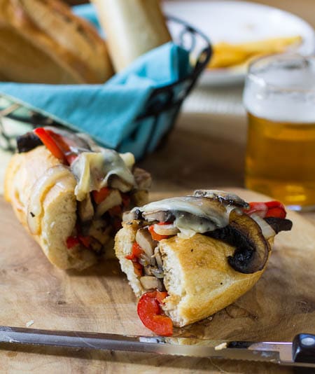 Portobello Cheesesteak cut in half with beer and bread in background.