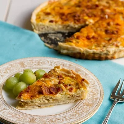 Slice of quiche on a plate with grapes.