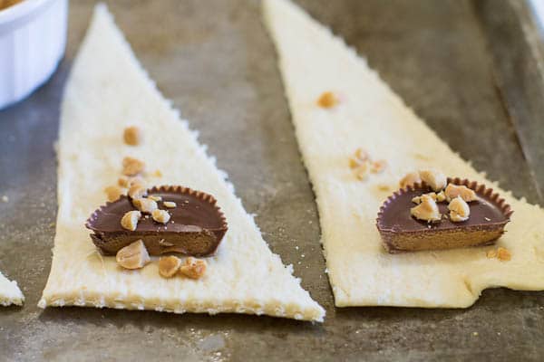 Triangles of crescent roll dough with Reese's cup and chopped peanuts on them.