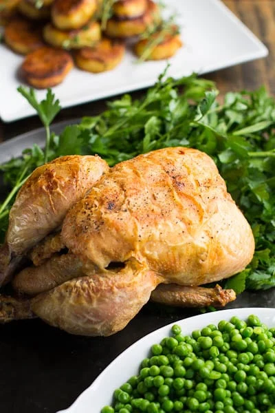 Roast Chicken on bed of parsley with peas and roasted potatoes.