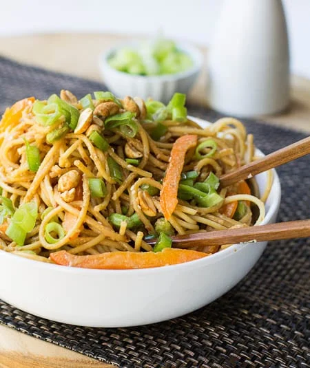 Bowl full of Sesame Peanut Noodles with chop sticks.