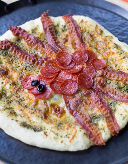 Spider Pizza with a spider made out of pepperoni and bacon.