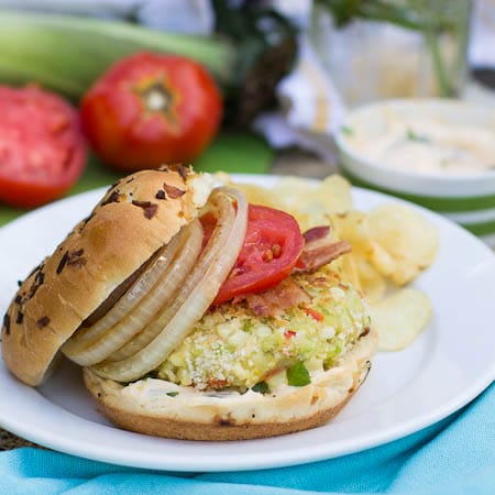 Succotash Burger on a bun with bacon, tomato, and griled onion.