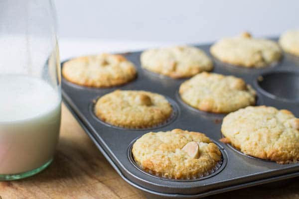 Muffins in muffin tin with jar of milk.